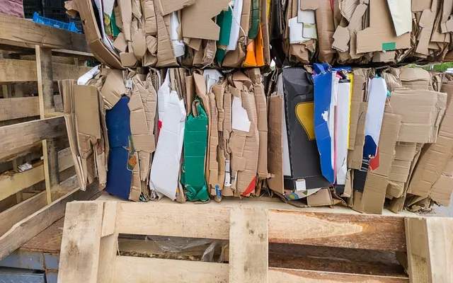 Baled waste cardboard packaging stacked on wooden pallets