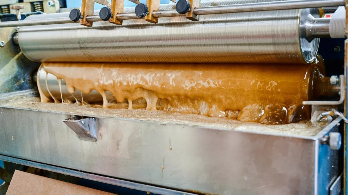 Molten hot-melt adhesive running over the roller and tray of a gluing unit