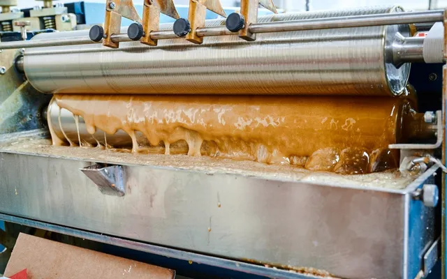 Molten hot-melt adhesive running over the roller and tray of a gluing unit