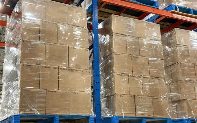 Wrapped pallets of corrugated cases stacked high in warehouse racking