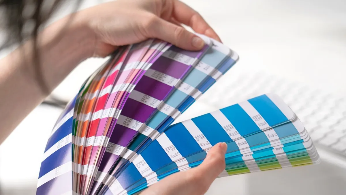 A fanned-out Pantone colour guide held open at the blues and magentas