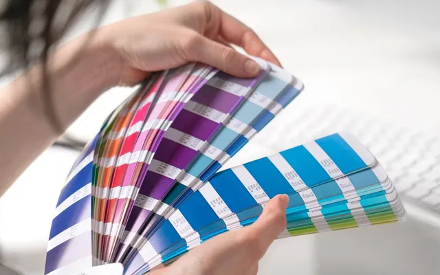 A fanned-out Pantone colour guide held open at the blues and magentas