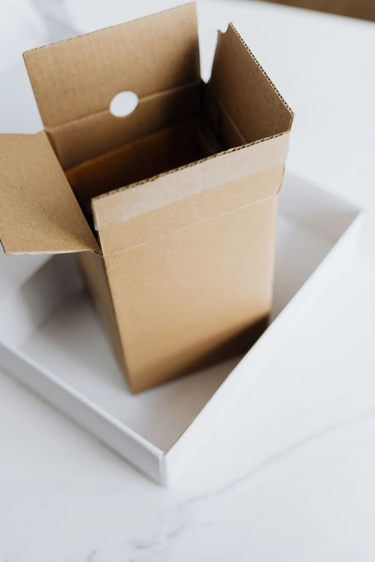 An open single-bottle corrugated gift box standing on a white presentation lid
