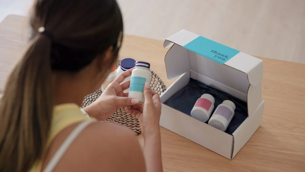 A subscriber opening a white mailer box with a thank you message printed inside the lid