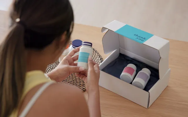 A subscriber opening a white mailer box with a thank you message printed inside the lid