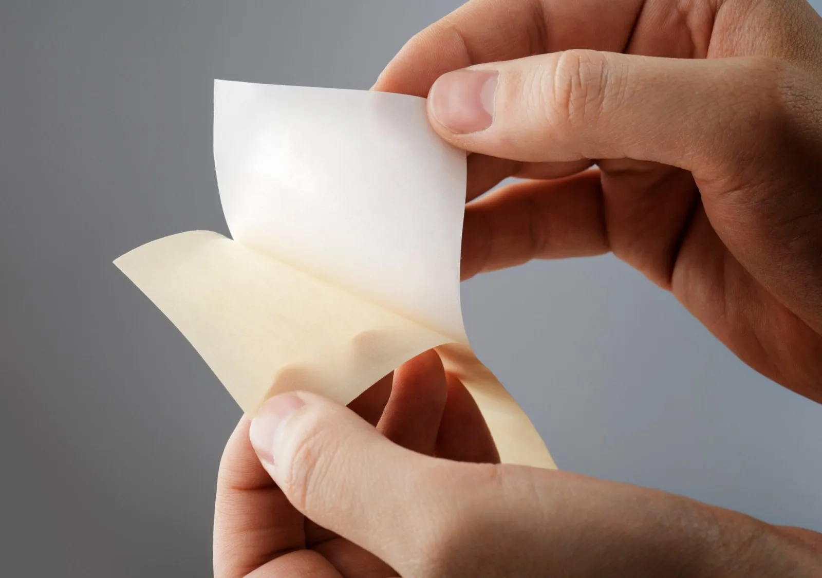 A release liner being peeled away from an adhesive-coated face