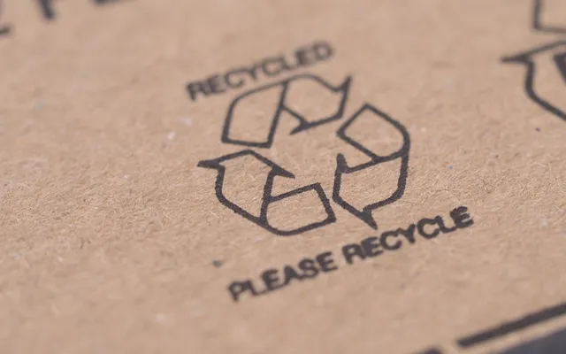 A close-up of a recycling mark printed in black ink on kraft corrugated board